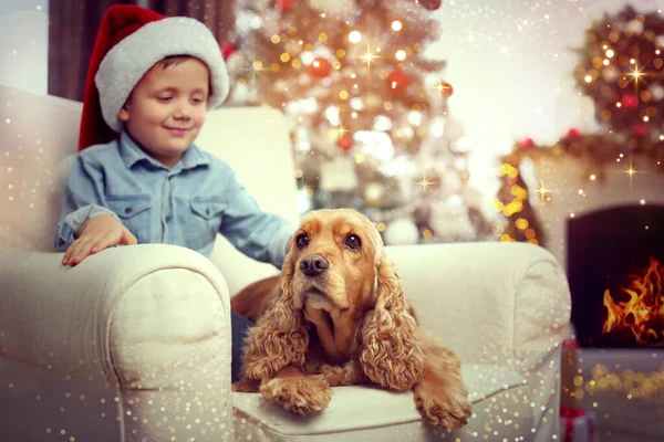 Cute little boy with English Cocker Spaniel in room decorated for Christmas. Magical festive atmosphere