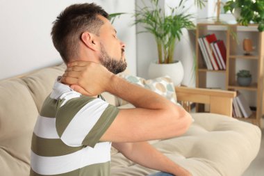 Odada boynu ağrıyan bir adam.