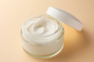 Bej arka planda bir kavanoz yüz kremi, yakın plan.