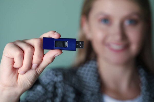 Женщина держит USB Flash Drive на зеленом фоне, сосредоточиться на руку