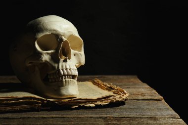 İnsan kafatası ve eski kitap ahşap masa üzerinde siyah arkaplan, metin için boşluk