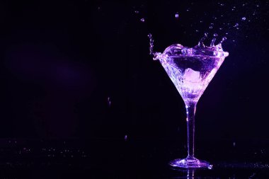 Buzlu bir bardak martini ve koyu arkaplanda neon ışıkları. Metin için boşluk