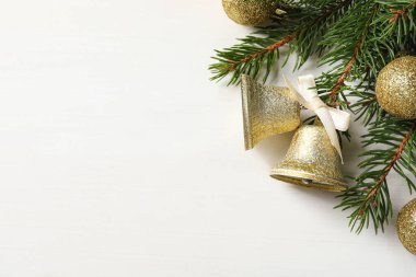 Noel çanları ve köknar ağacı dalları beyaz ahşap masa üzerinde, düz yatıyordu. Metin için boşluk