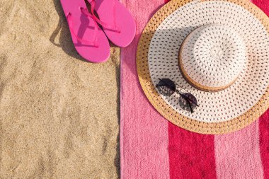 Plaj havlusu, terlik, hasır şapka ve kumdaki güneş gözlüğü. Metin için boşluk