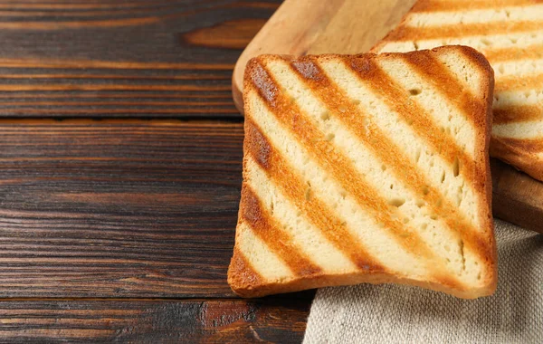 Slices of tasty toasted bread on wooden table, closeup. Space for text