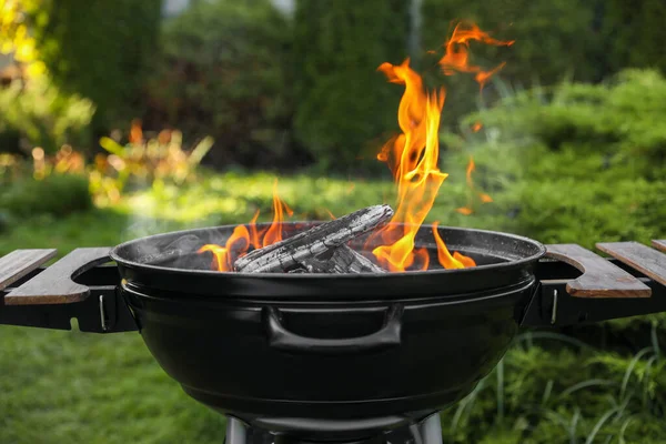 Portable barbecue grill with fire flames outdoors, closeup