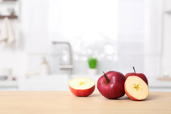 Whole and cut apples on wooden counter in kitchen, space for text