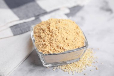 Beyaz mermer masada cam kasede susam unu.