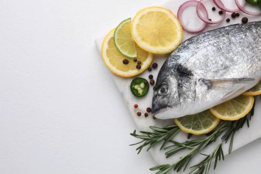 Beyaz masada taze dorado balığı ve baharatlar, üst manzara. Metin için boşluk