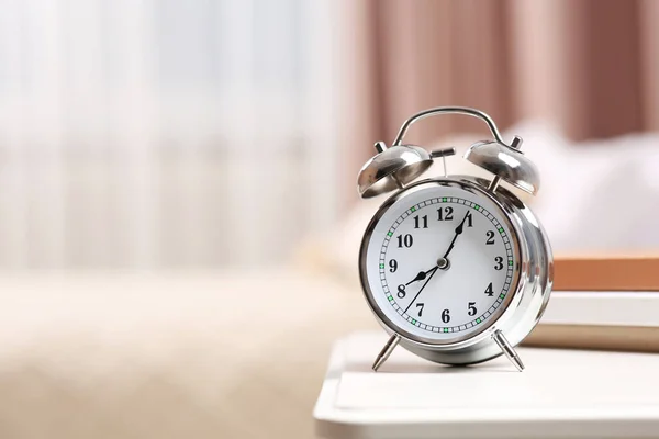 Silver alarm clock on white nightstand indoors. Space for text