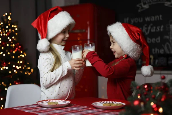 Cute little children with milk at table in dining room. Christmas time