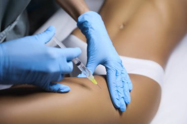 Genç bir kadın kuaförde bacak enjeksiyonu yaptırıyor.