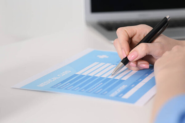 Врач заполняет медицинскую карту пациента за столом в клинике, крупным планом