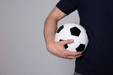 Açık gri arka planda futbol topu olan atletik bir adam, yakın plan. Metin için boşluk