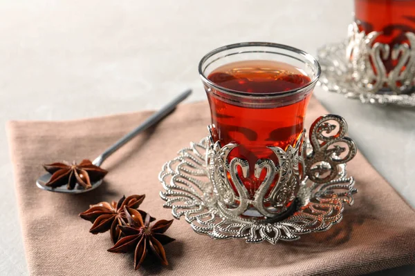 Glasses of traditional Turkish tea in vintage holders and anise stars on table, closeup