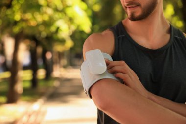 Güneşli bir günde parkta antrenmandan sonra kan basıncını modern monitörle ölçen adam, yakın plan. Metin için boşluk