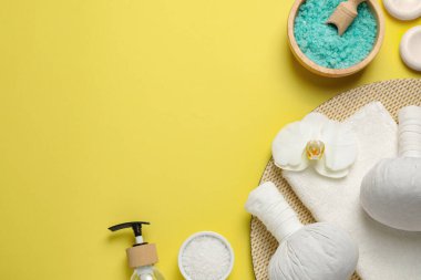Güzel bir spa kompozisyonu, bitkisel masaj torbaları ve sarı arka planda farklı bakım ürünleri, düz yatak. Metin için boşluk