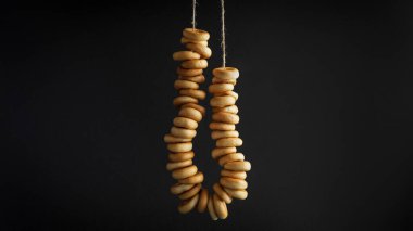 Siyah arka planda asılı lezzetli halka şekilli Sushki (kuru simit) demeti