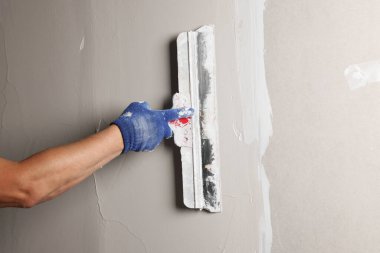 Profesyonel işçi duvar macun bıçağıyla sıva yapıyor, yakın plan.