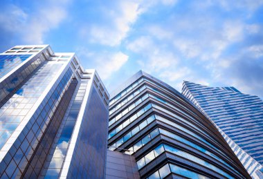 Beautiful blue sky with clouds reflecting in windows. Low angle view of modern buildings clipart