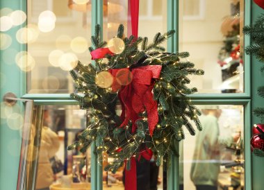 Güzel Noel çelengi. Kapısında kurdele ve şenlik ışıkları asılı.