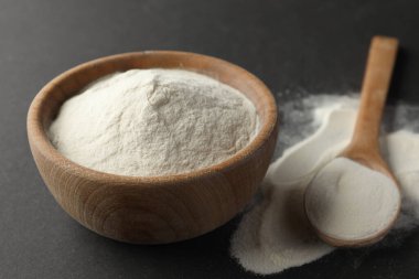 Siyah arka planda kaşık ve bir kase agar pudrası, yakın plan.