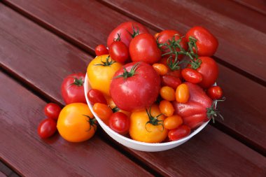 Tahta masanın üzerinde taze domateslerle dolu bir kâse.