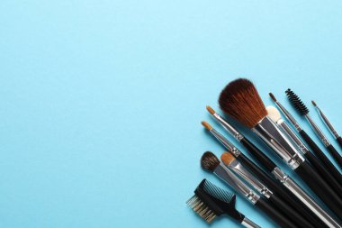 Açık mavi arka planda düz bir makyaj fırçası seti. Metin için boşluk