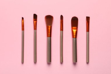 Pembe arka planda makyaj fırçaları, düz yatış