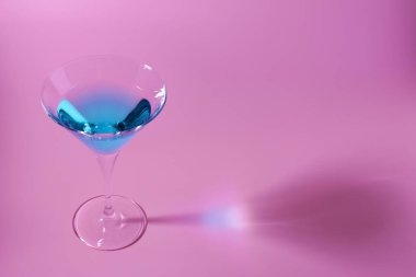 Pembe arka planda lezzetli bir kokteyl ile martini bardağı, mesaj için yer.