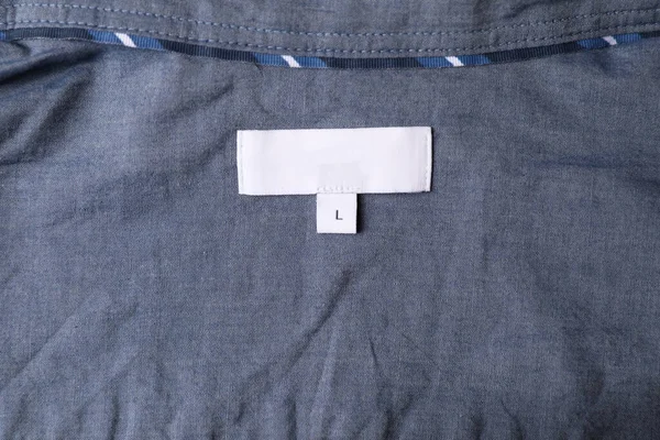 Clothing label on grey garment, top view