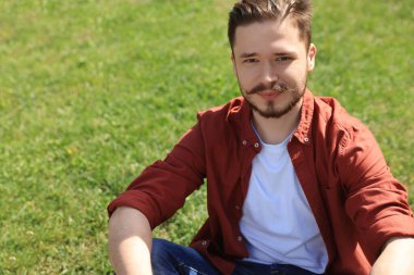 Dışarıdaki yeşil çimlerde oturan yakışıklı adam. Metin için boşluk