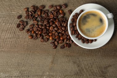 Ahşap masada bir fincan aromatik kahve ve fasulye. Metin için boşluk