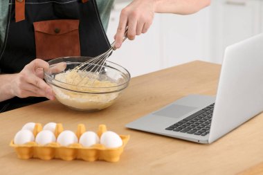 İçerideki ahşap masada çevrimiçi video ile yemek pişirmeyi öğrenen adam, yakın plan. Hobi zamanı.