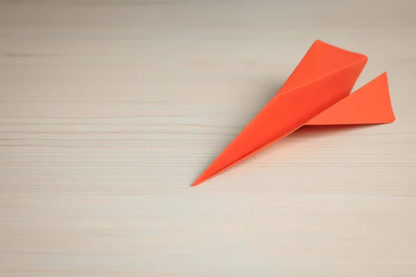 Handmade orange paper plane on beige wooden table. Space for text