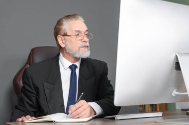 Büyük patron modern ofiste ahşap masada çalışıyor.