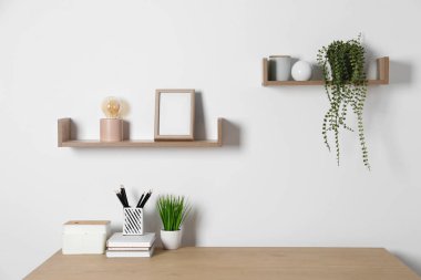 Evinde beyaz duvarın yanında ahşap masası olan rahat bir iş yeri.
