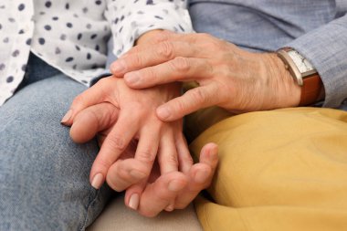 Evde el ele tutuşan olgun bir çift, yakın çekim. Randevu ajansı