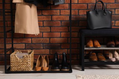 Ayakkabı depolama tezgahı ve tuğla duvarın yanında aksesuarlar olan şık bir koridor. İç tasarım