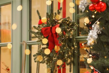 Güzel Noel çelengi. Kapısında kurdele ve şenlik ışıkları asılı.