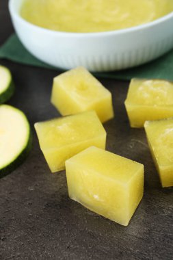 Donmuş kabak püresi küpleri ve gri masada taze kabak, yakın plan.