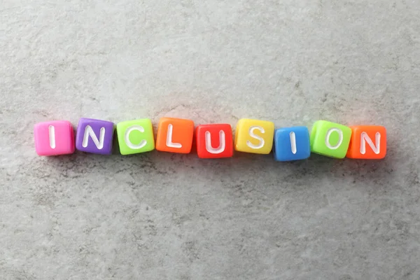 Colorful cubes with word Inclusion on light grey background, flat lay