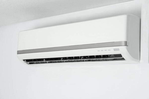 Modern air conditioner on white wall indoors