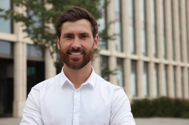 Portrait of handsome bearded man on city street, space for text