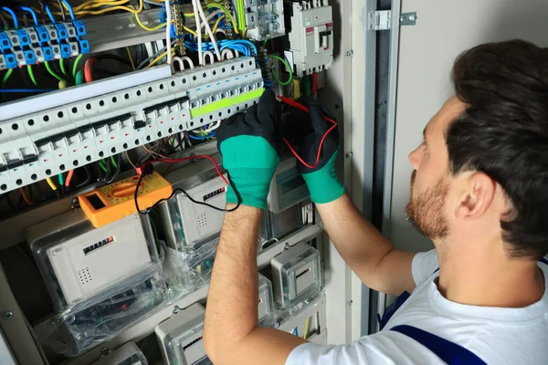 Electrician checking electric current with multimeter indoors, closeup