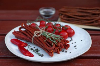 Lezzetli kuru sosisler (kabanosy) ve ahşap masa malzemeleri.