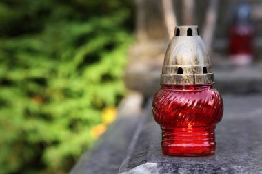 Mezarlıkta granit yüzeyinde yanan mum bulunan kırmızı mezar feneri, metin için alan