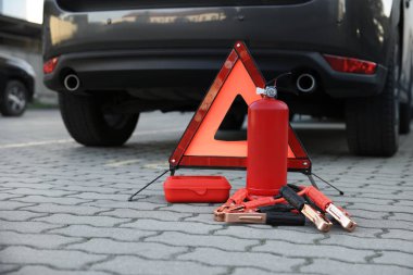 Emergency warning triangle and safety equipment near car, space for text clipart