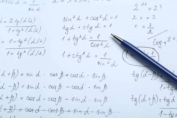 Sheet of paper with different mathematical formulas and pen, top view