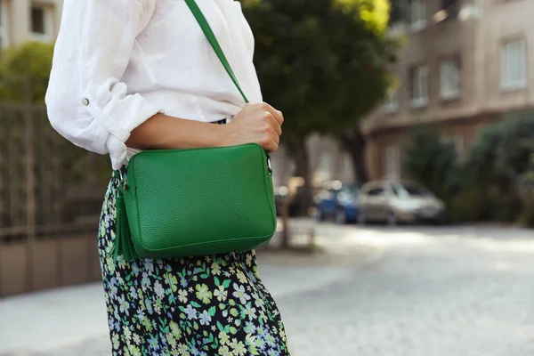 Woman with stylish green bag on city street, closeup. Space for text